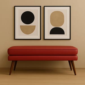 Könnte beinhalten: Eine rote, gepolsterte Bank mit Holzbeinen steht unter zwei gerahmten abstrakten Kunstdrucken. Die Drucke zeigen schwarze und beige geometrische Formen auf cremefarbenem Hintergrund. Die Bank ist ein modernes Möbelstück.