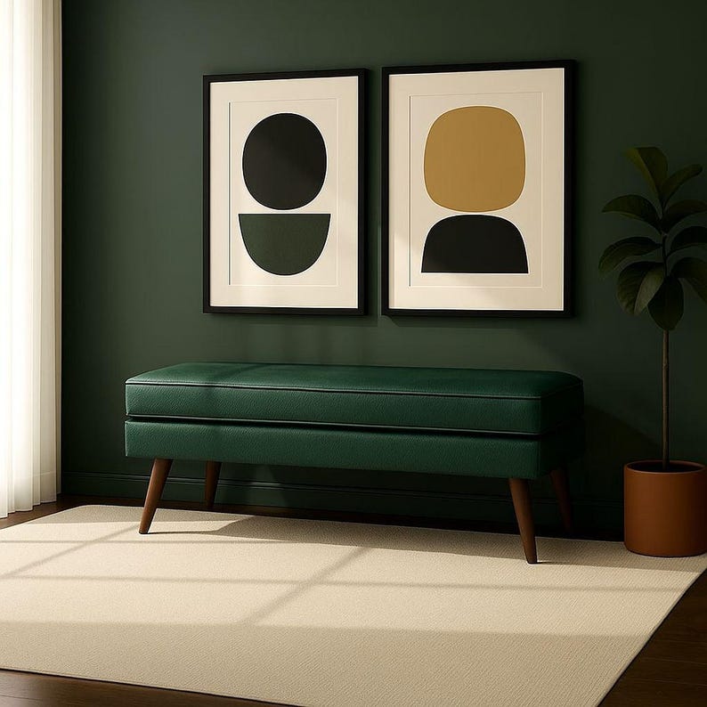 May include: A dark green bench with wooden legs sits on a light beige rug. Two framed abstract art prints hang on a dark green wall. A potted plant is on the right side of the image. The bench is a mid-century modern style.