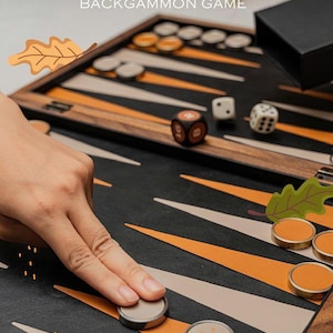 May include: A premium backgammon game set with a black playing surface, orange and white triangles, and wooden frame. Includes dice, round game pieces, and a black box. The text "PREMIUM BACKGAMMON GAME" is visible.