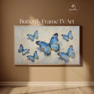 Puede incluir: Una obra de arte enmarcada con mariposas azules con detalles dorados sobre un fondo claro. La obra se titula "Butterfly Frame TV Art" y se muestra en una pared.