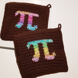 May include: Two brown crocheted pot holders with a rainbow colored pi symbol on each.