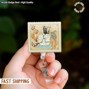 May include: A badge reel with a rectangular design featuring cartoon cats breaking a block of ice. The badge reel has a white retractable cord and a clear plastic strap. The text "Arcylic Badge Reel - High Quality" is visible.