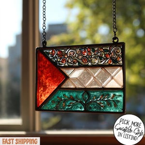 May include: A rectangular stained glass suncatcher with a black metal frame, suspended by a chain. The design features red, white, and green sections with floral and geometric patterns. The text "Pick More Suncatcher Style in Listing!" is visible.
