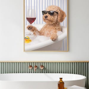 Pode incluir: Uma impressão de arte de parede emoldurada apresentando um cão de pelo encaracolado castanho claro usando óculos de sol pretos, sentado numa banheira branca cheia de espuma. O cão segura um copo de vinho tinto e um pequeno pato de borracha amarelo flutua na água com sabão.