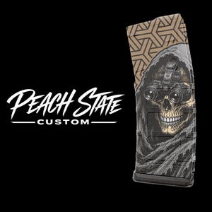 May include: A black magazine with a skull graphic wearing night vision goggles. The magazine has a tan geometric pattern at the top and the words "Peach State Custom" in white.