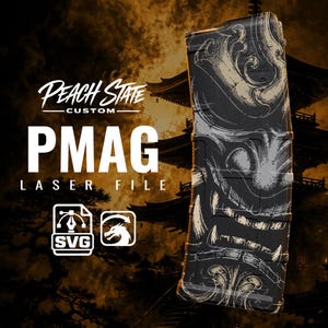 Könnte beinhalten: Ein schwarzes Magazin mit einem detaillierten, weiß lasergravierten Design einer stilisierten Maske mit scharfen Zähnen. Das Bild enthält den Text PEACH STATE CUSTOM PMAG LASER FILE sowie SVG- und Drachen-Symbole vor einem dunklen, rauchigen Hintergrund.