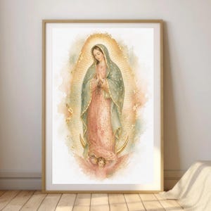 Pode incluir: Uma impressão de arte emoldurada representando a Virgem de Guadalupe em estilo aguarela. Ela veste um vestido rosa e um manto azul-petróleo com estrelas douradas, sobre uma lua crescente sustentada por um anjo com asas rosas e halo dourado.