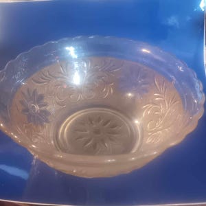May include: A clear glass bowl with a scalloped rim and an intricate floral pattern.