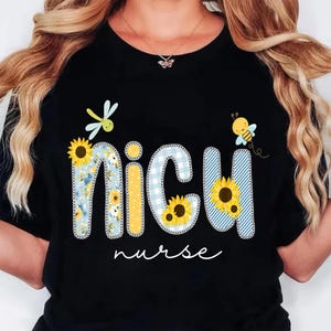 May include: Black t-shirt with the words "NICU nurse" in a whimsical design. The letters are decorated with sunflowers, blue gingham, and floral patterns, with a dragonfly and bee accents.