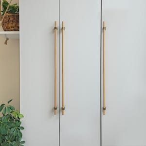 May include: White cabinet doors with two sets of wooden cabinet pulls with brass accents.
