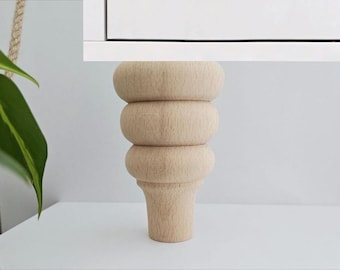 May include: A set of four wooden furniture legs with a rounded, stacked design. The legs are unfinished and ready to be stained or painted.