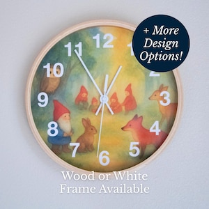 Puede incluir: Un reloj de pared redondo con marco de madera clara que presenta una ilustración en acuarela de animales del bosque y gnomos. La esfera muestra números y manecillas blancas. El texto dice + More Design Options! y Wood or White Frame Available.