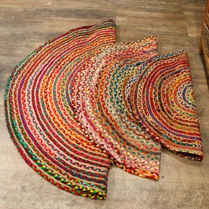 May include: A round, multi-colored jute rug with a braided design. The rug is made of natural fibers and has a rustic, bohemian style.
