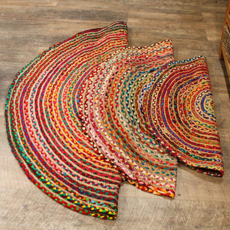May include: A round, multi-colored jute rug with a braided design. The rug is made of natural fibers and has a rustic, bohemian style.