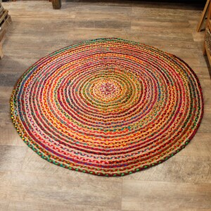 May include: A round, multi-colored jute rug with a concentric circle pattern. The rug is made of natural fibers and has a rustic, bohemian style.