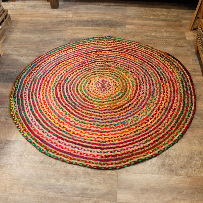 May include: A round, multi-colored jute rug with a concentric circle pattern. The rug is made of natural fibers and has a rustic, bohemian style.