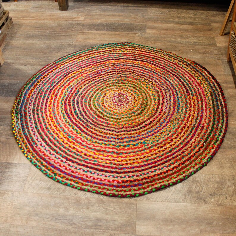 May include: A round, multi-colored jute rug with a concentric circle pattern. The rug is made of natural fibers and has a rustic, bohemian style.