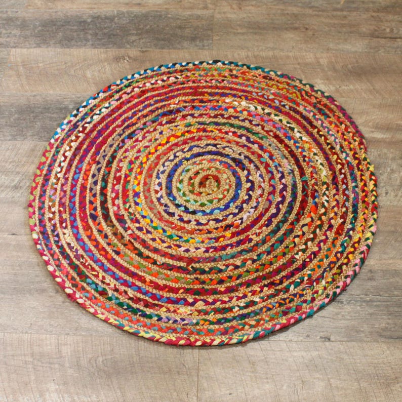 May include: A round, multi-colored jute rug with a braided design. The rug has a variety of colors, including red, blue, green, yellow, and orange.
