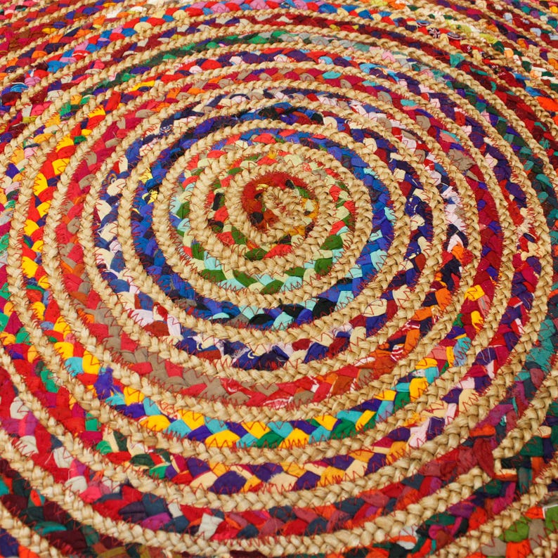 May include: A round, multi-colored braided rug with a circular pattern. The rug is made of natural fibers and features a variety of colors, including red, blue, green, yellow, and brown.