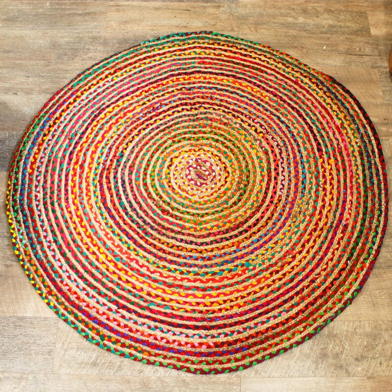 May include: A round, multi-colored jute rug with a concentric circle pattern. The rug is made of natural fibers and has a rustic, bohemian style.