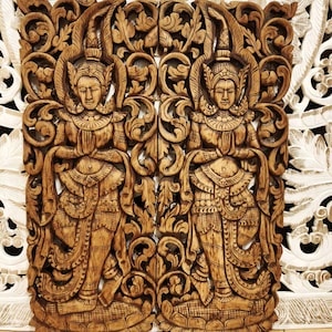 May include: A pair of rectangular wooden wall panels featuring intricate hand-carved relief designs of figures in traditional attire with hands pressed together in a prayer gesture, surrounded by elaborate floral and scrolling leaf patterns.