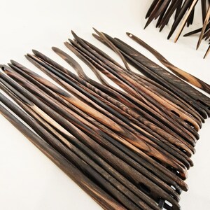 May include: A set of wooden knitting needles with a dark brown and light brown wood grain pattern. The needles are arranged in a fan shape and are all the same length.