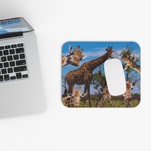 Könnte beinhalten: Ein farbenfrohes Mauspad mit einer Collage von Giraffen in einer Savannenlandschaft. Die Giraffen sind braun und haben lange Hälse und Flecken. Der Hintergrund ist ein blauer Himmel mit weißen Wolken.