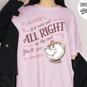 May include: A light pink t-shirt with the text "It'll turn out ALL RIGHT in the end. You'll see." and a cartoon teapot illustration. The shirt has a Comfort Colors Blossom logo in the upper right corner.