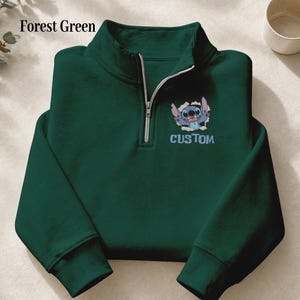 May include: Forest green quarter-zip sweatshirt featuring a cartoon character graphic and the word "CUSTOM". The sweatshirt has a silver zipper and a high collar. The text "Forest Green" is in the upper left corner.