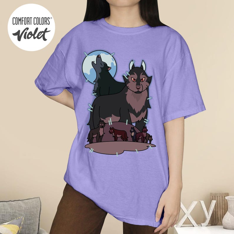 May include: Violet Comfort Colors t-shirt featuring a wolf pack design. The graphic includes a large wolf with red eyes, a howling wolf, and several smaller wolves. The shirt has the Comfort Colors logo in a white circle.