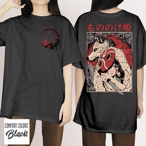 May include: Black Comfort Colors t-shirt featuring a red and black graphic on the front and back. The front graphic shows a figure in a circle. The back graphic displays a wolf, a person wearing a mask, and Japanese text.