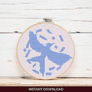 May include: A blue bird cross stitch pattern on white Aida cloth, mounted in a round embroidery hoop. The bird is stylized and has a geometric design.