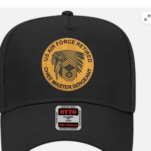 May include: Black baseball cap with a circular emblem featuring the text "US AIR FORCE RETIRED CHIEF MASTER SERGEANT" and an illustration of a Native American chief. The cap also has a "OTTO" label.