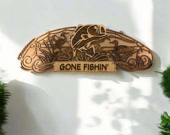 May include: A wooden sign with a carved fish, birds, and reeds. The sign reads "Gone Fishin'" in a decorative font.