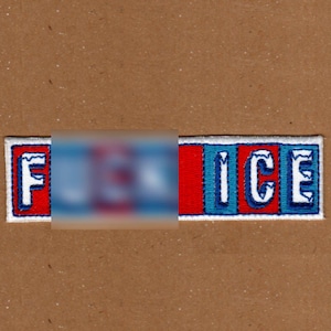May include: Embroidered patch with the word "ICE" in white letters, with a red and blue colour scheme. The first part of the word is blurred out. The patch is rectangular with a white border, set against a brown background.