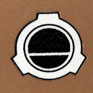 May include: A white embroidered patch with a black circle and a horizontal line inside. The circle is surrounded by a white ring.
