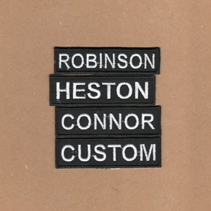 May include: Four black fabric patches with white text. The patches read "Robinson", "Heston", "Connor", and "Custom".