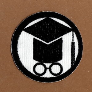 May include: Black and white embroidered patch featuring a graduation cap and glasses. The cap has a tassel and the glasses are round.
