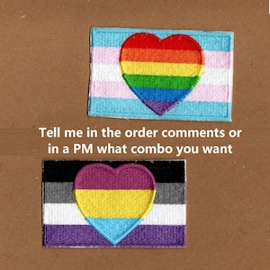 May include: Two embroidered patches featuring heart designs. One patch has a rainbow heart on a light blue, pink, and white background. The other patch has a heart in purple, yellow, and blue on a black, gray, white, and purple background. Text on the image reads: Tell me in the order comments or in a PM what combo you want.