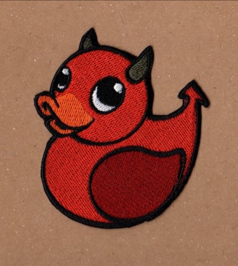 K&ouml;nnte beinhalten: Roter gestickter Aufn&auml;her mit einem Cartoon-Teufel-Enten-Motiv mit H&ouml;rnern und Schwanz.