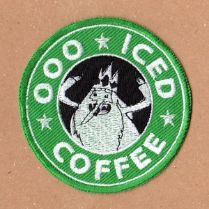 May include: Green and white embroidered patch with a cartoon character holding a cup of coffee. The text "OOO ICED COFFEE" is written around the character.