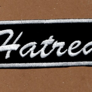 May include: Black and white embroidered patch with the word "Hatred" in a white cursive font.
