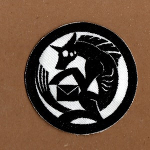 May include: Black and white embroidered patch featuring a stylised wolf holding an envelope. The wolf is surrounded by a circular border.
