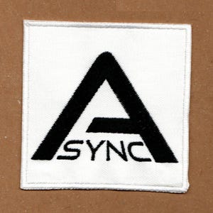 Peut inclure: Un &eacute;cusson carr&eacute; brod&eacute; blanc pr&eacute;sentant une lettre A majuscule noire en gras avec le mot SYNC &eacute;crit en lettres majuscules noires sous la barre transversale du A. L'&eacute;cusson poss&egrave;de une bordure cousue blanche et une surface en tissu textur&eacute;.