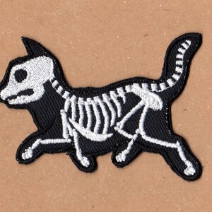 May include: Black embroidered iron-on patch of a skeleton cat with white bones.
