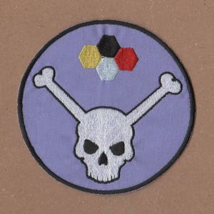 May include: A purple embroidered patch with a white skull and crossbones. The skull has black eyes. Above the skull is a cluster of five hexagonal shapes in yellow, black, red, and white.