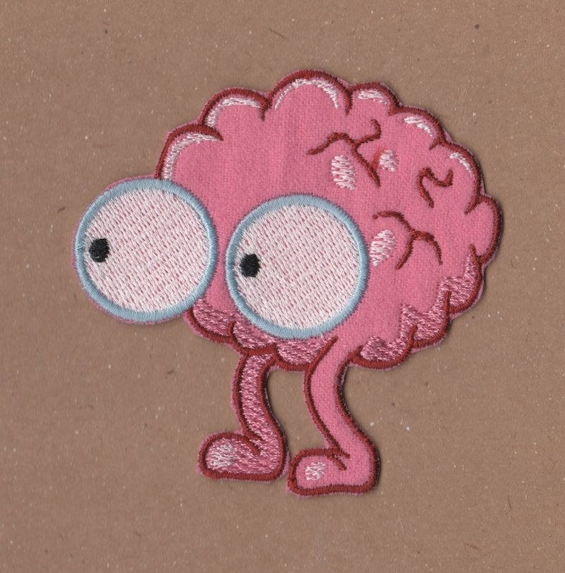 May include: Pink embroidered brain with large white eyes and two pink legs. The brain has a detailed design of the folds and wrinkles of a human brain.