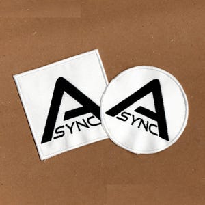 以下が含まれることがあります： 白い背景に太い黒文字のAとSYNCというテキストが刺繍された、正方形と円形の2つの布製ワッペン。どちらのワッペンもデザインが中央に配置されており、縁は白い糸で丁寧に縫い合わされています。
