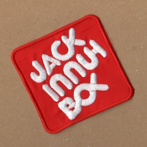 Op de afbeelding: Rode vierkante patch met witte geborduurde tekst die "Jack in the Box" luidt.