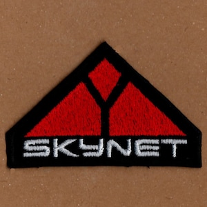 Może przedstawiać: Naszywka haftowana w kolorze czarnym i czerwonym z napisem "SKYNET" w białych literach.